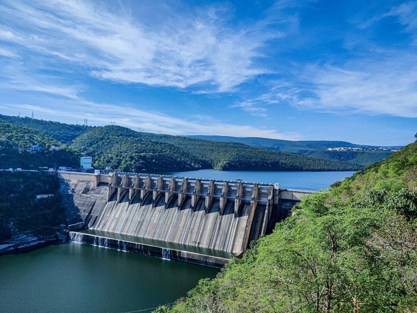 Barragem hidrelétrica cercada por vegetação, com reservatório ao fundo