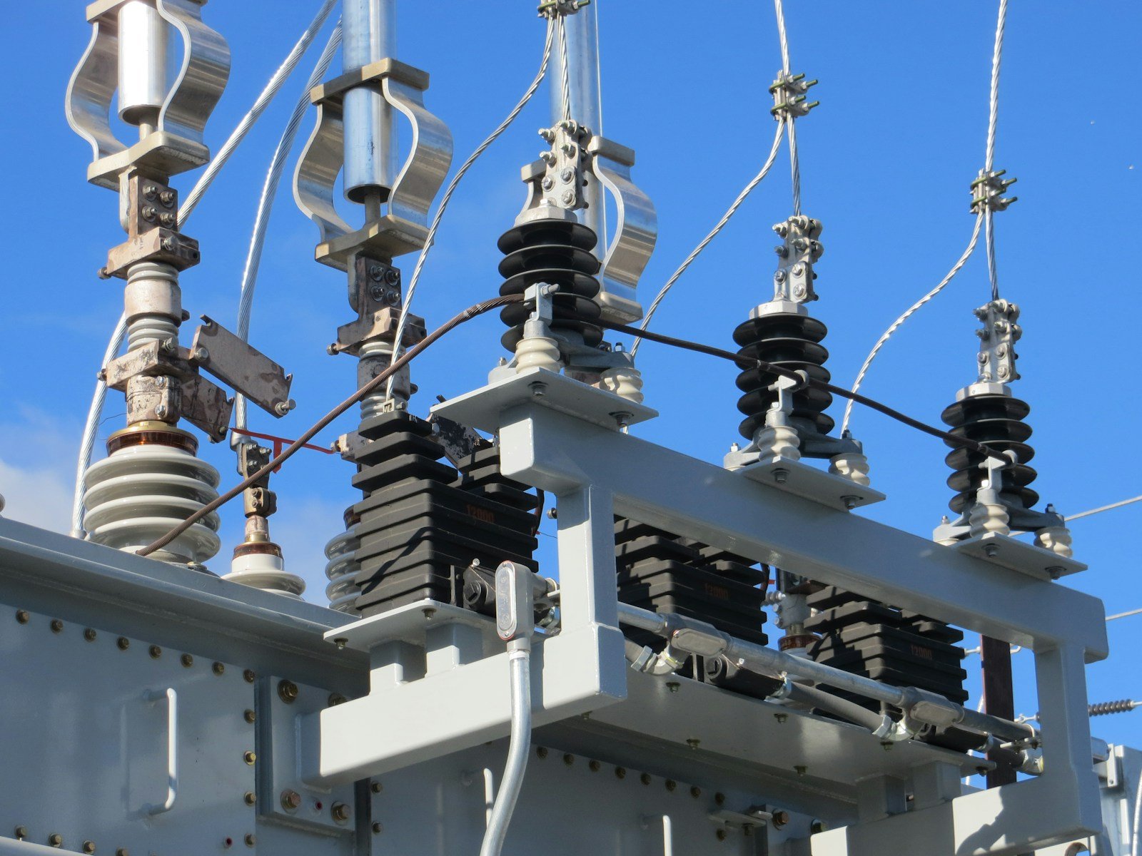 Isoladores e componentes metálicos de um equipamento em subestação elétrica.